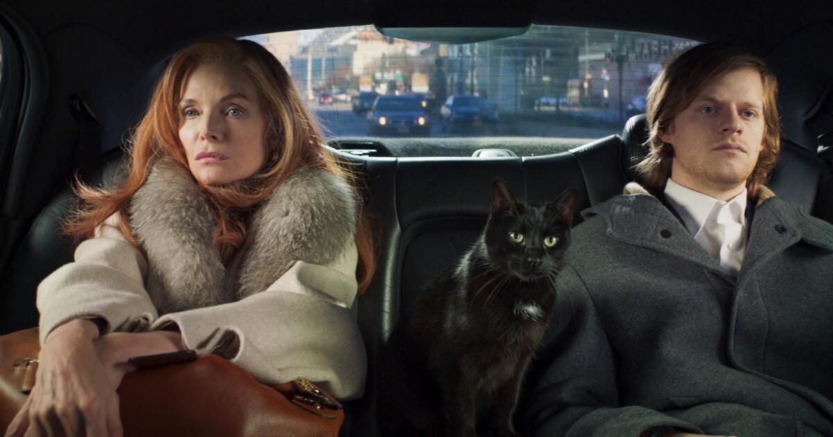 Woman and boy sit in the back of a cab with a black cat.
