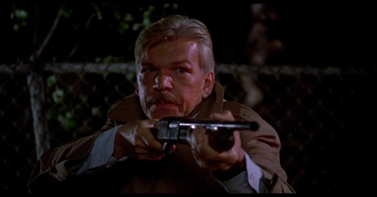 Tom Atkins segurando uma espingarda