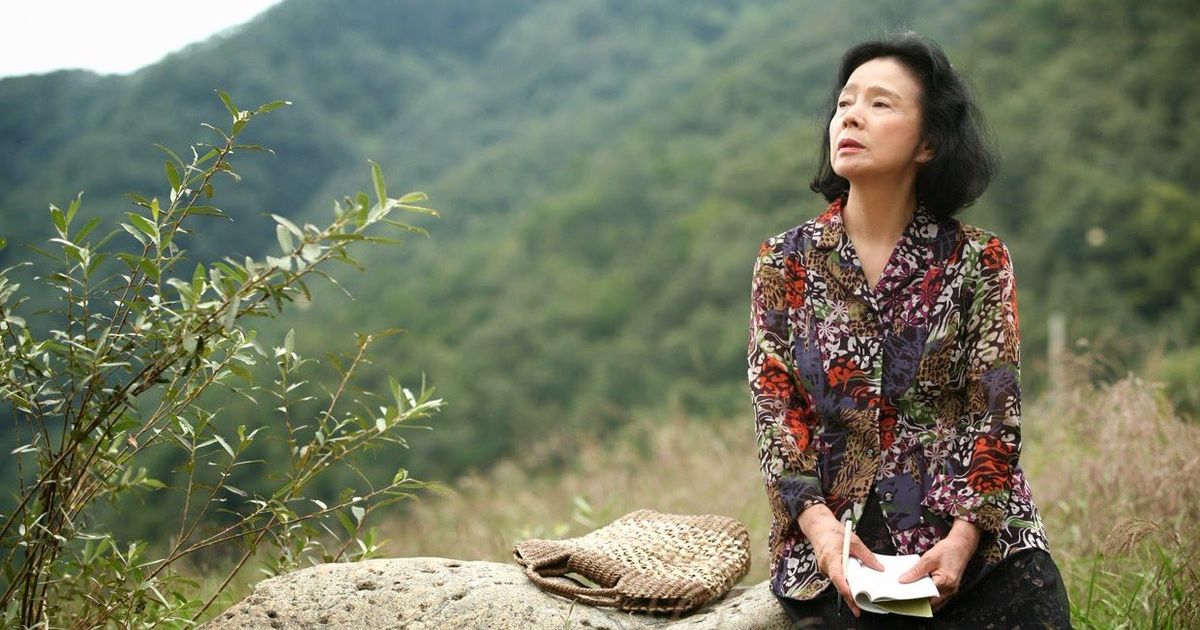 Woman sits in nature with a notebook and pen.