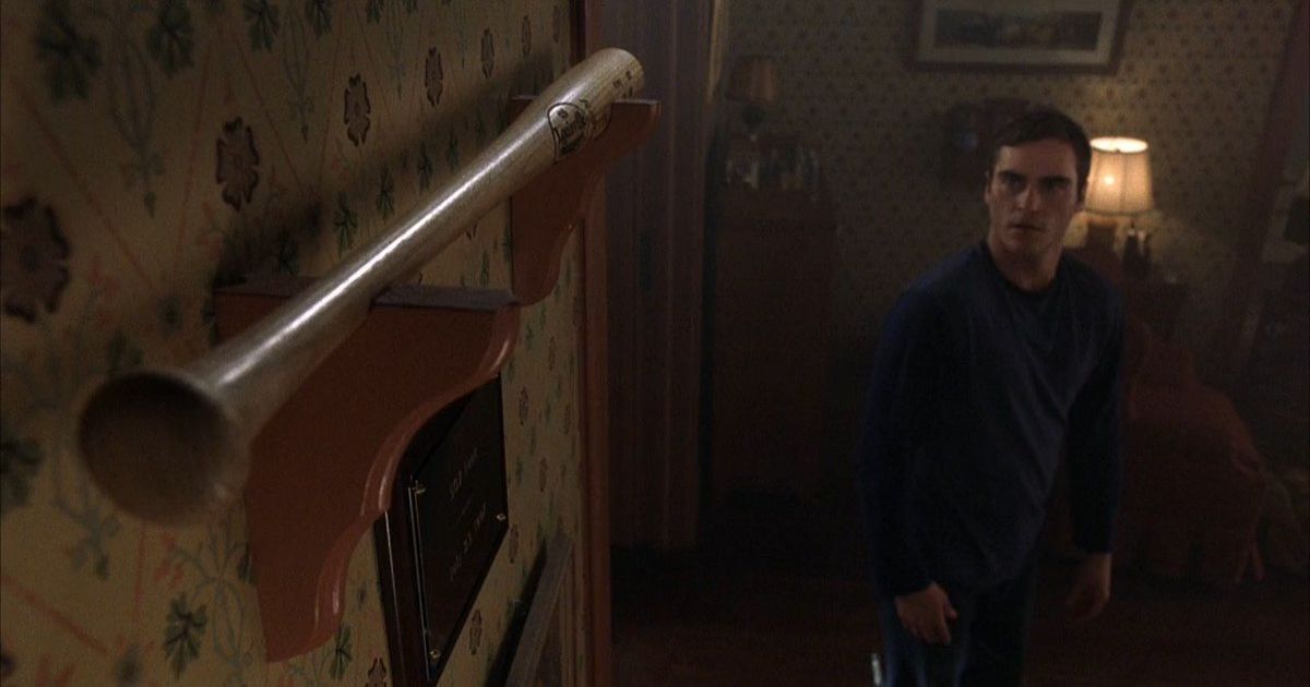 Joaquin Phoenix looks at baseball bat above mantle in Signs