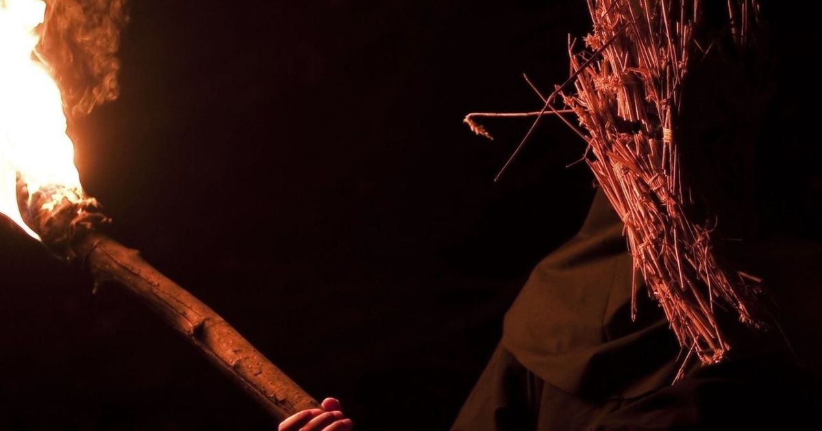 A creepy cult member burns a torch in Kill List.