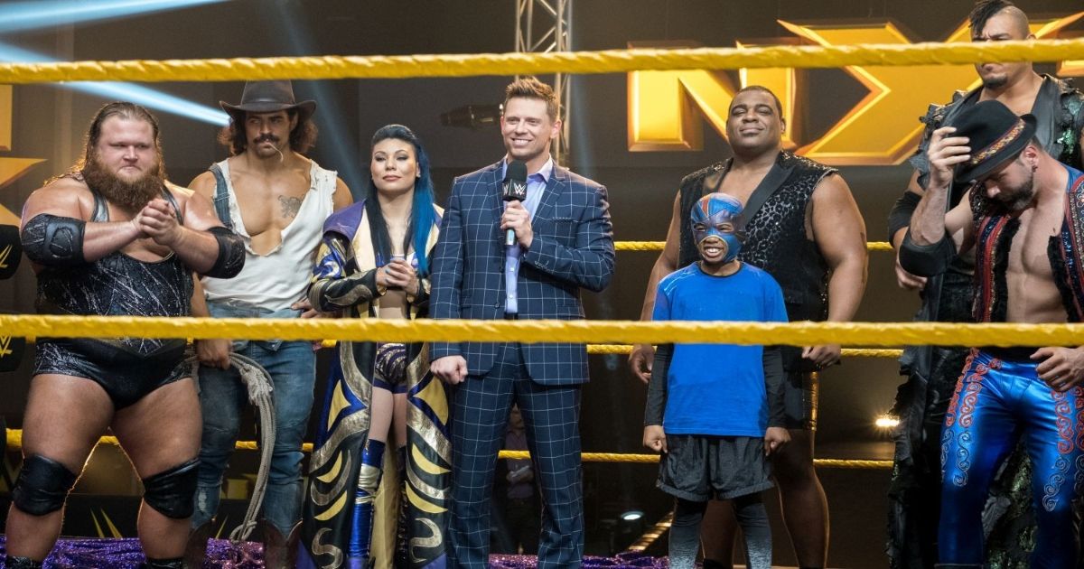 Several people standing in a wrestling ring with a young boy