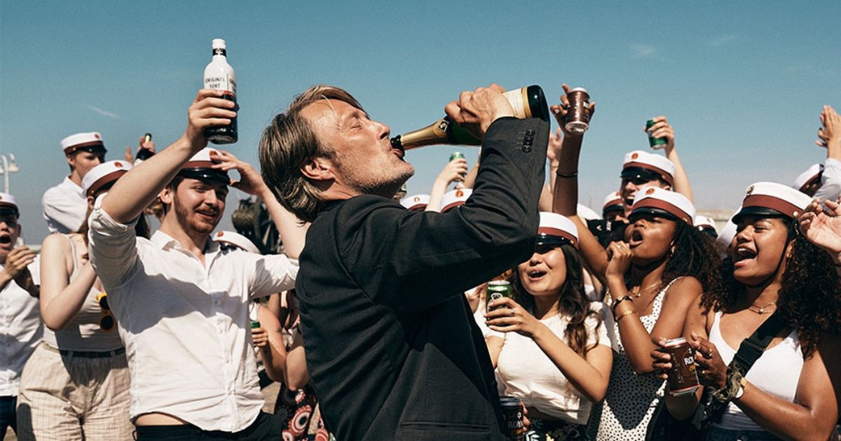 Man drinks champagne straight from bottle as cheering crowd eggs him on in Another Round