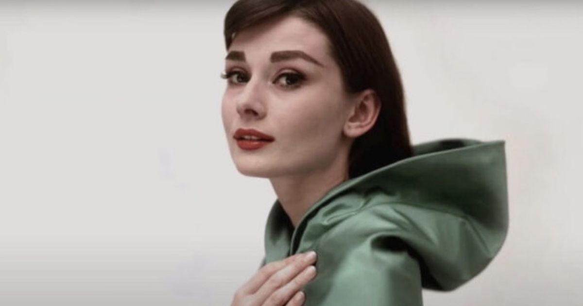 Audrey Hepburn poses in green cloak.