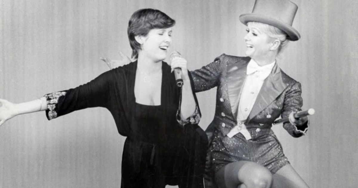 Carrie Fisher and Debbie Reynolds sit next to each other singing.