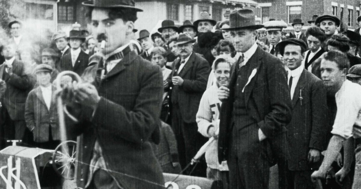 Group of people stand behind Charlie Chaplin.