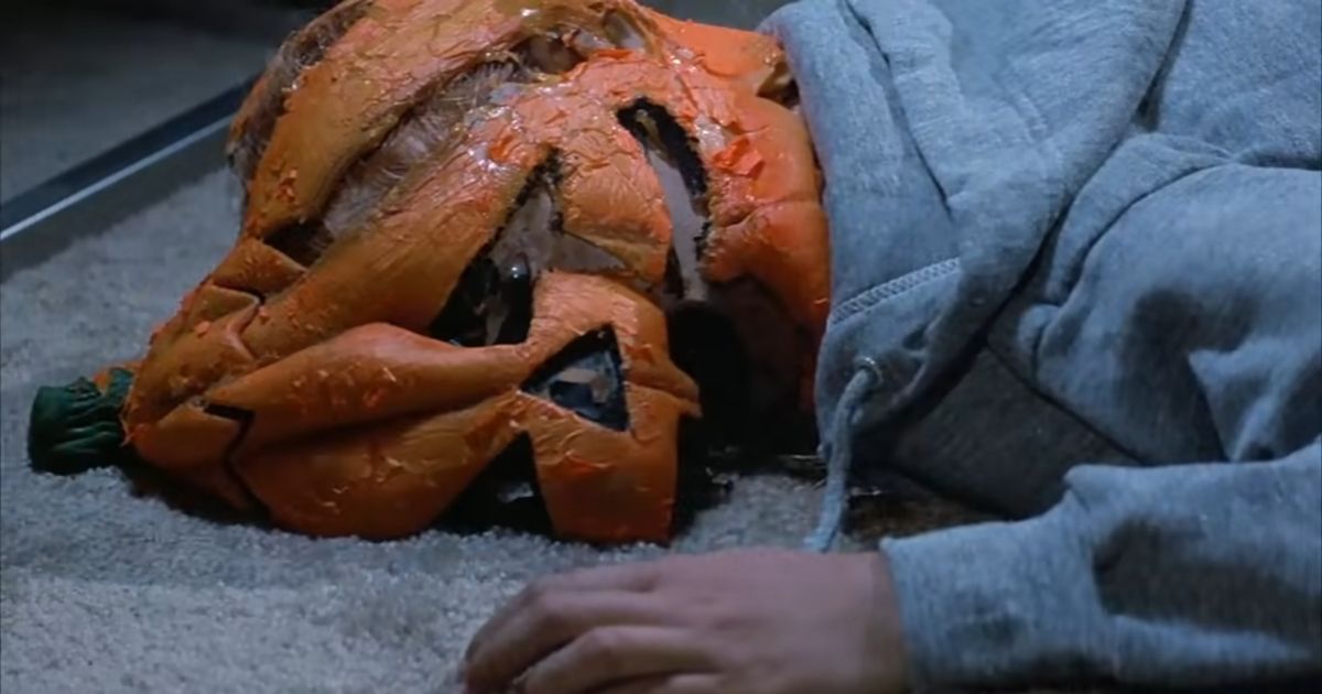 A person lying on the ground with a smashed pumpkin on their head in Halloween III Season of the Witch 