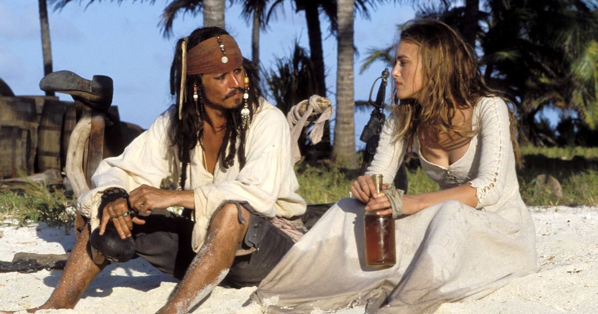 Jack sparrow and elizabeth sit on the beach in Pirates of the Caribbean The Curse of the Black Pearl