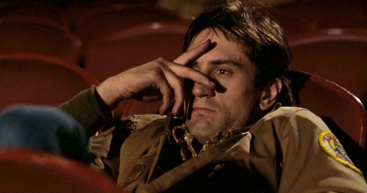 Robert DeNiro (Travis Bickle) sits in a movie theater partially covering his eyes in Taxi Driver