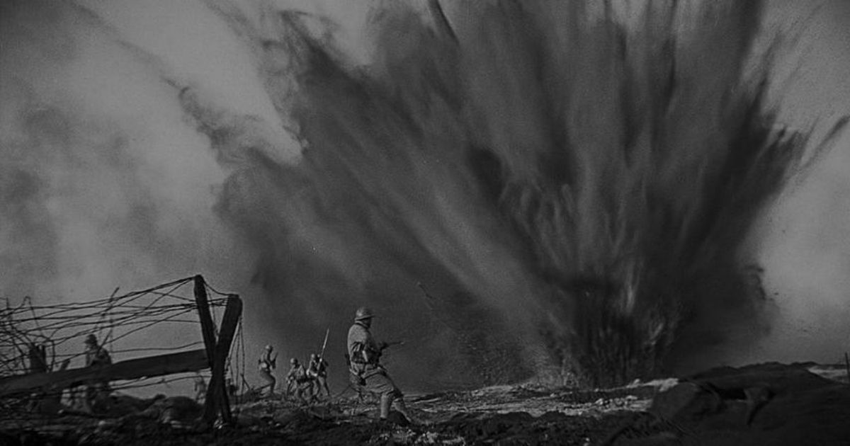 Several soldiers stand and fire into a large dusty explosion.
