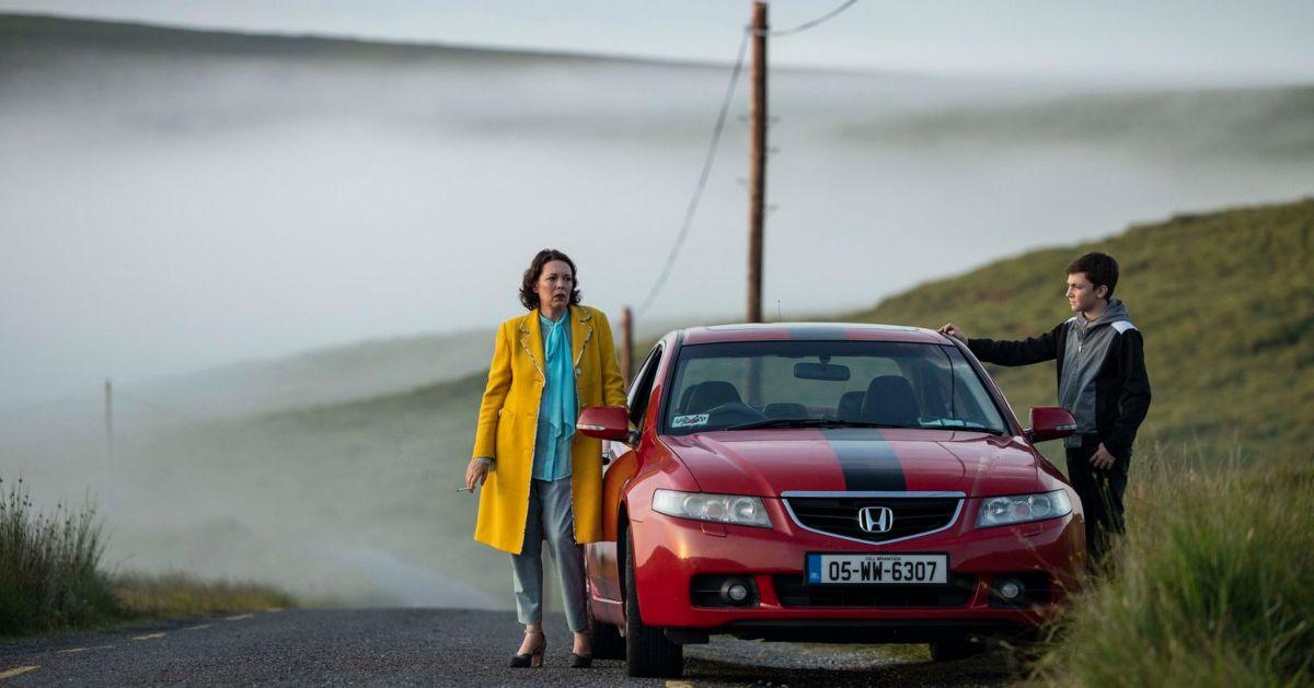 Olivia Colman and Charlie Reid by a car in the 2022 movie Joyride