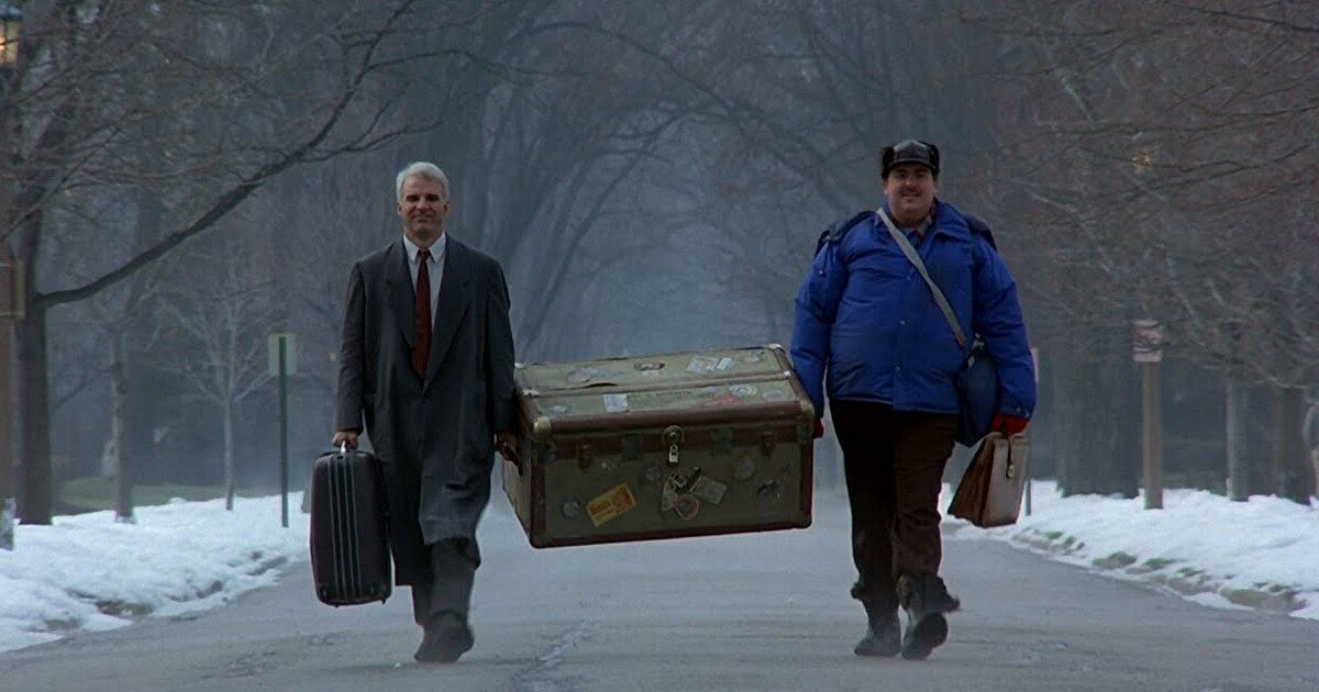  Steve Martin and John Candy carry a giant suitcase in Planes, Trains and Automobiles