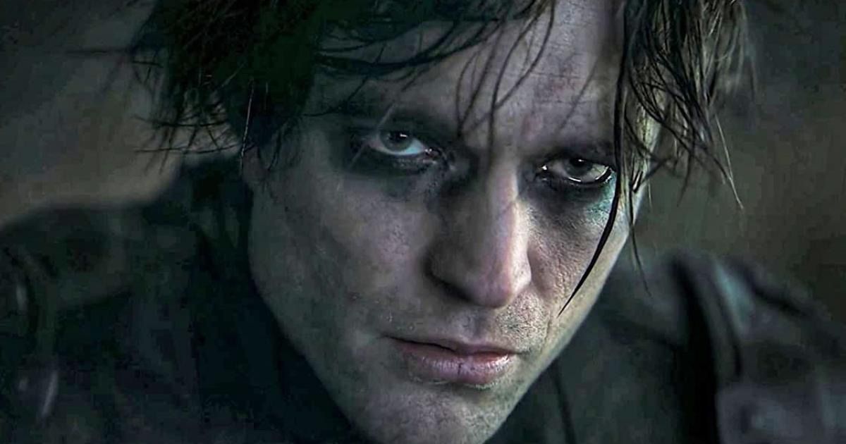 Robert Pattinson in his Batman suit with his mask off, wearing eyeliner with messy hair in The Batman.