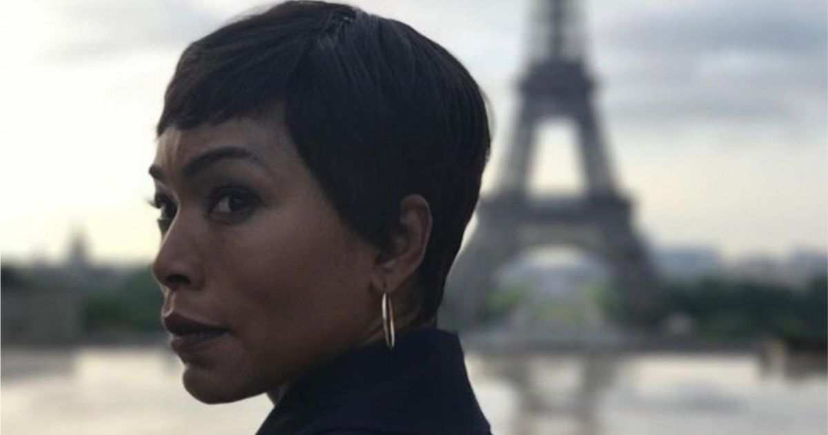 A woman looks over her shoulder, with the Eiffel Tower in the background