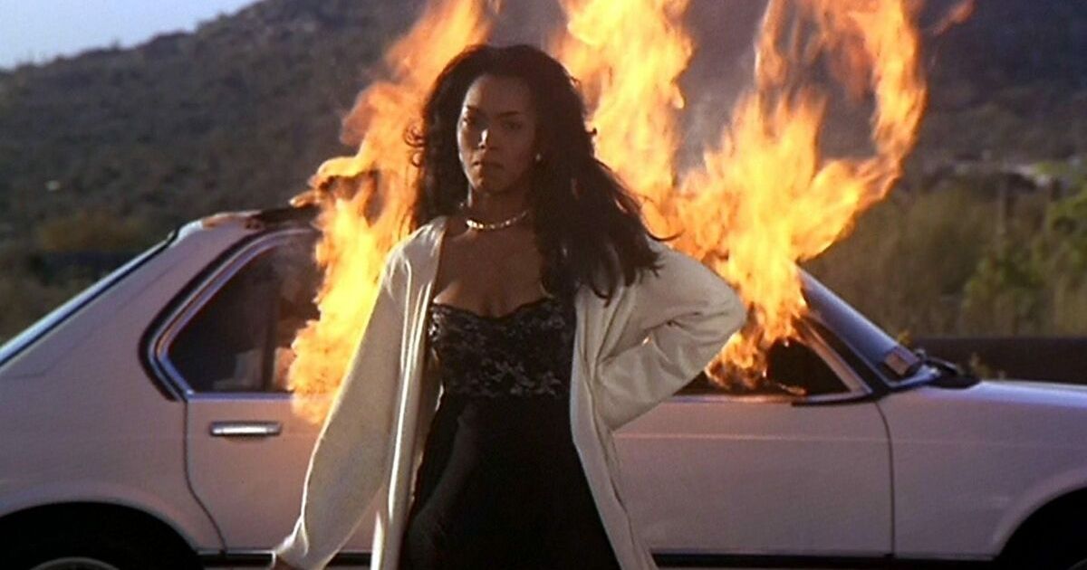 A woman walking away from a car on fire