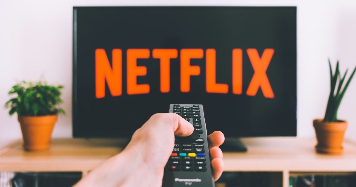 A Person Holding a Remote Pointed at a TV Saying Netflix