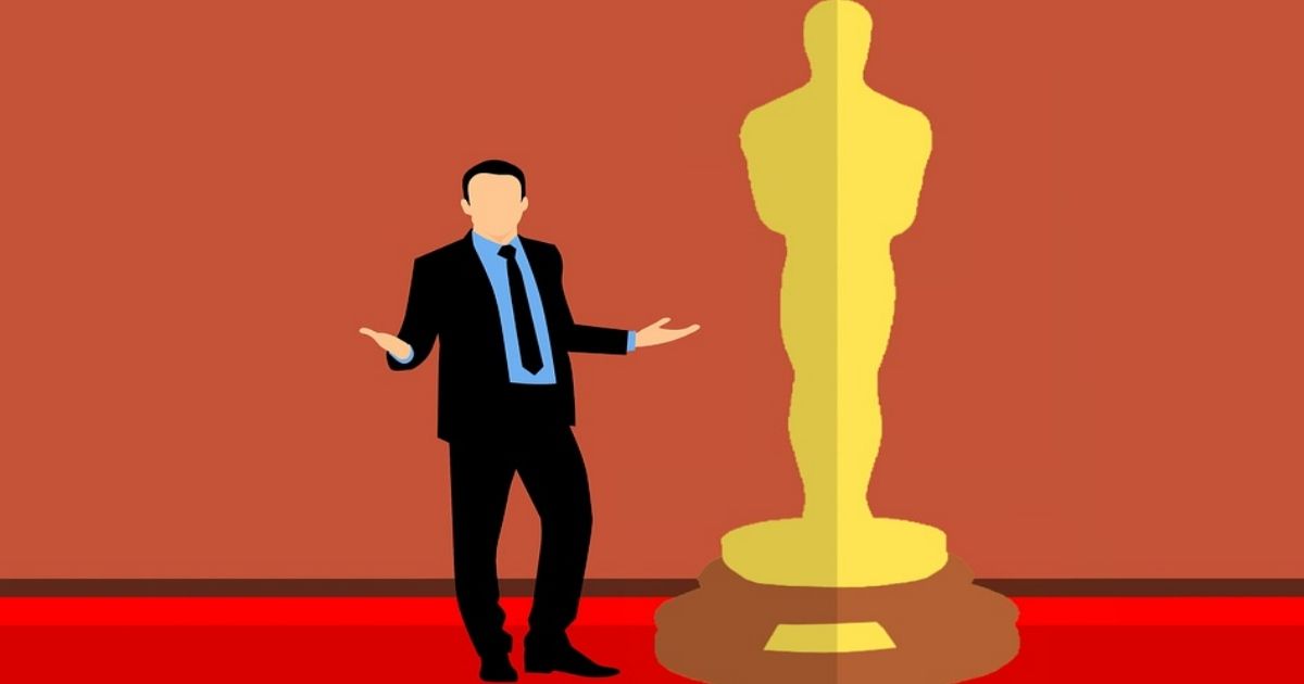 Man in a suit standing by giant Oscar trophy, snubbed by the Academy Awards