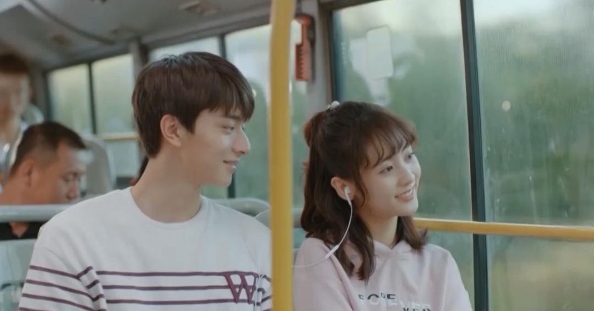 Girl and guy share headphones on bus