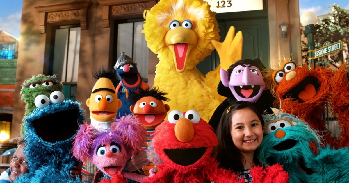 The Sesame Street characters along with some children waves to the viewers.