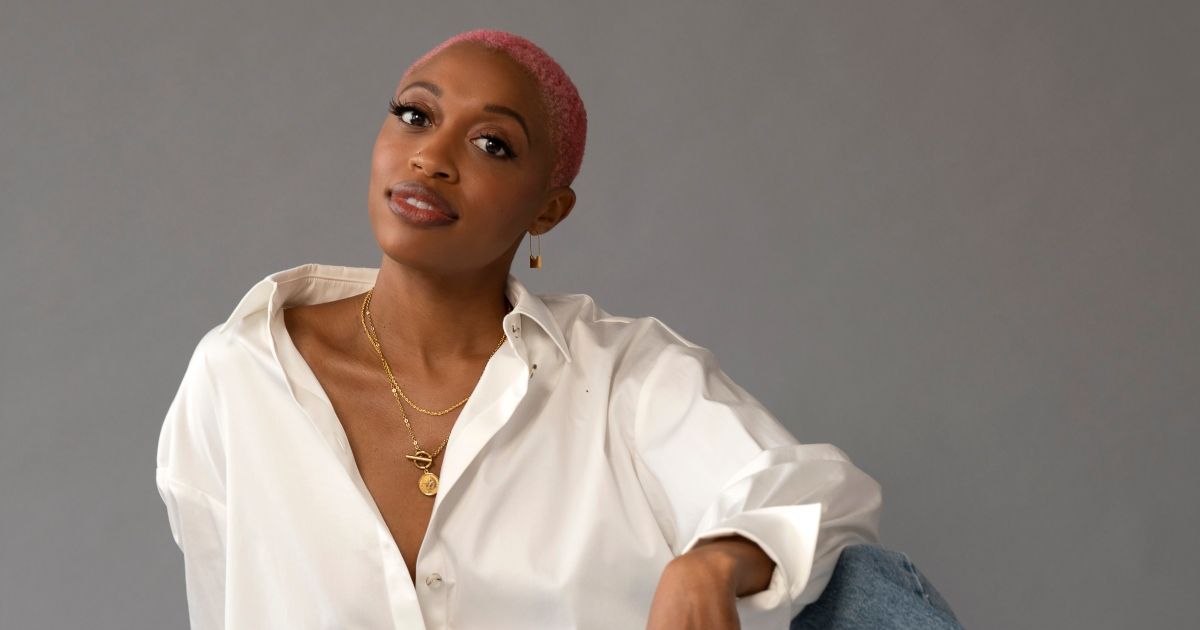 A Black woman with short pink hair poses for the camera