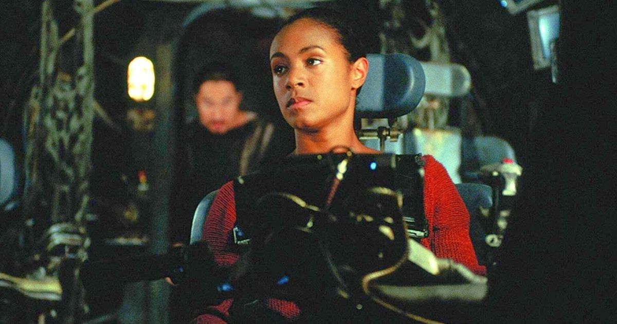 Jada Pinkett Smith sitting in a chair with several control panels around her in The Matrix.