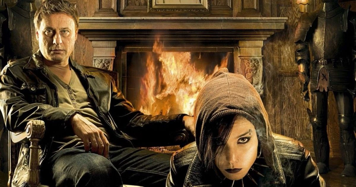 Lisbeth and the man sit by the fireplace in Girl With the Dragon Tattoo