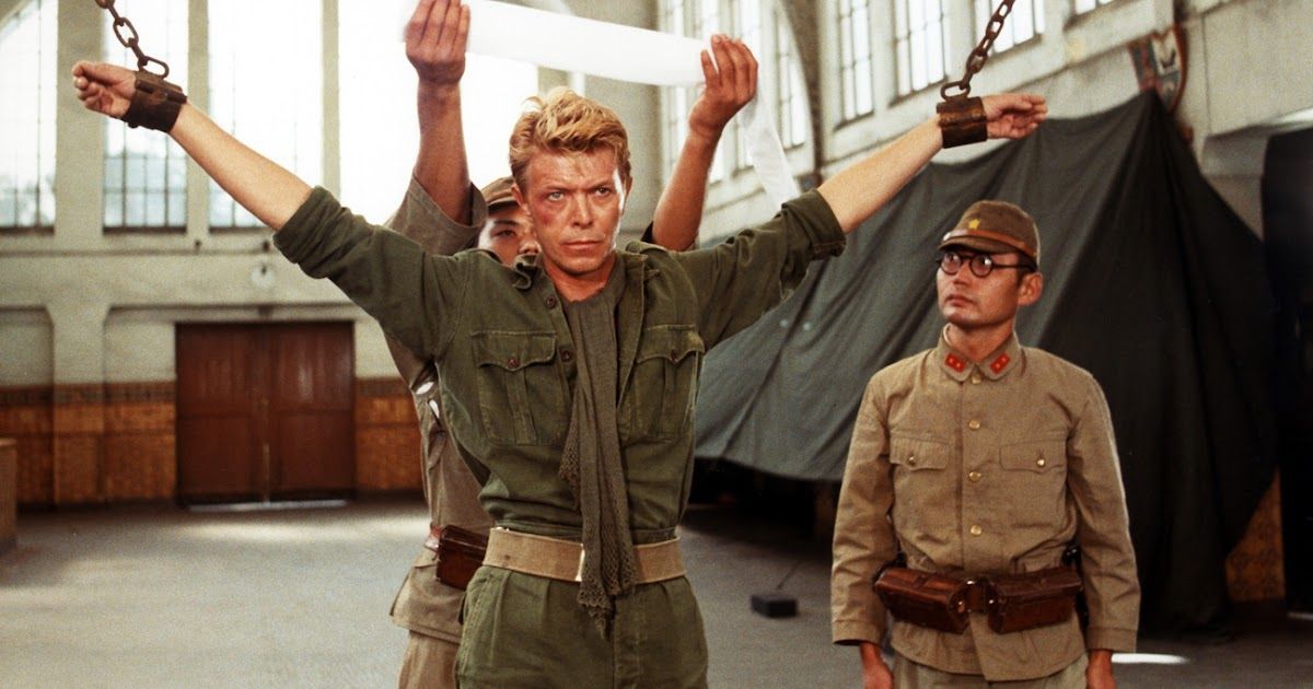David Bowie is chained before two Japanese soldiers in Merry Christmas, Mr. Lawrence
