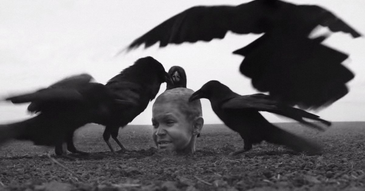 A young boy buried to his neck is pecked by crows in The Painted Bird