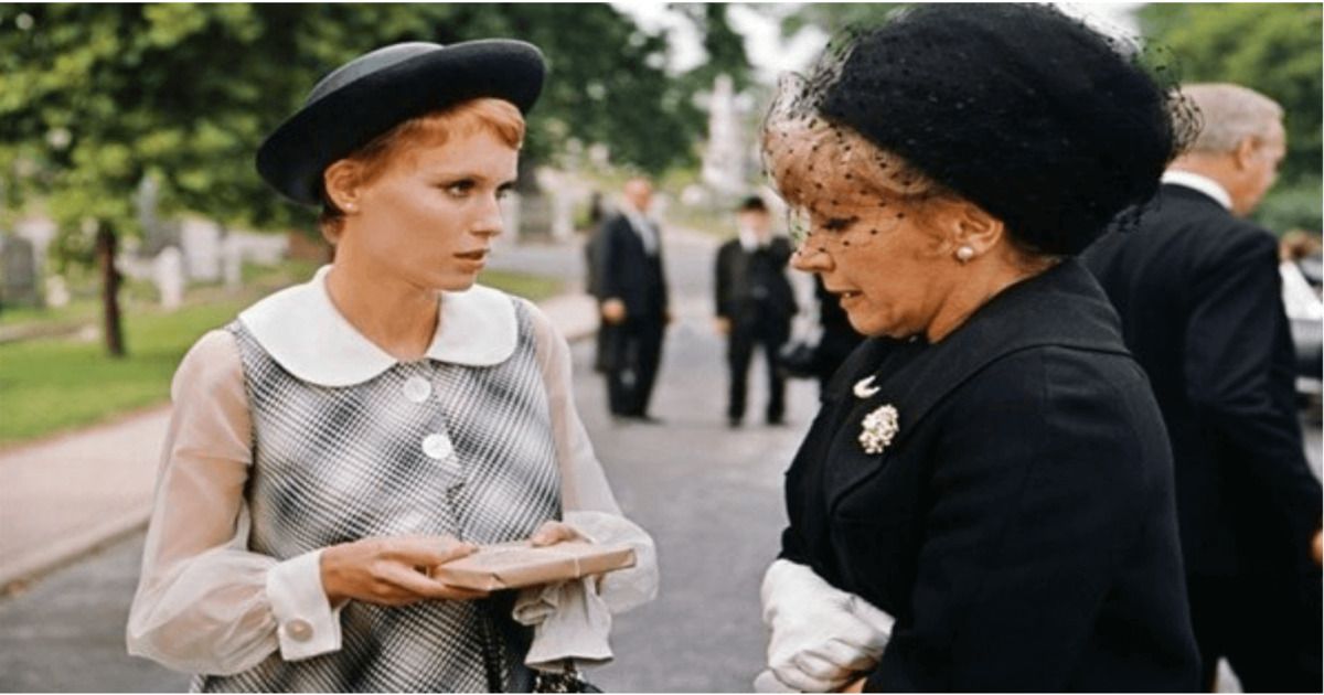 Rosemary em vestido reto anos 60 com estampa de alto contraste, botões grandes, grande gola redonda branca, mangas transparentes, punhos largos e chapéu bretão preto.