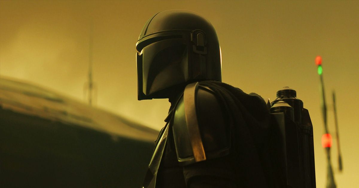 The Mandalorian with his helmet against a yellow sky