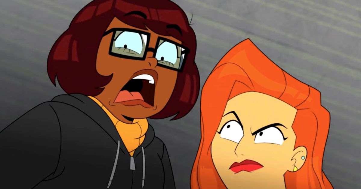 Velma gritando enquanto Daphne olha para ela com raiva com fundo cinza.