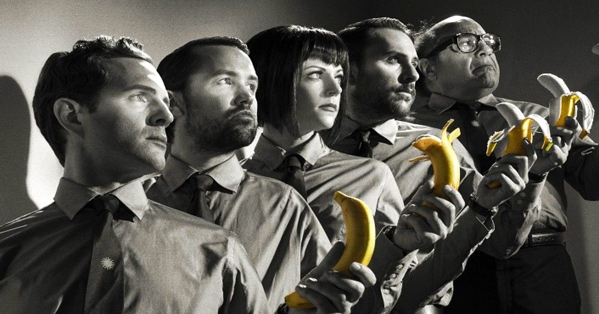 It's Always Sunny in Philadelphia crew poses with bananas in a black and white photo on the stairs.
