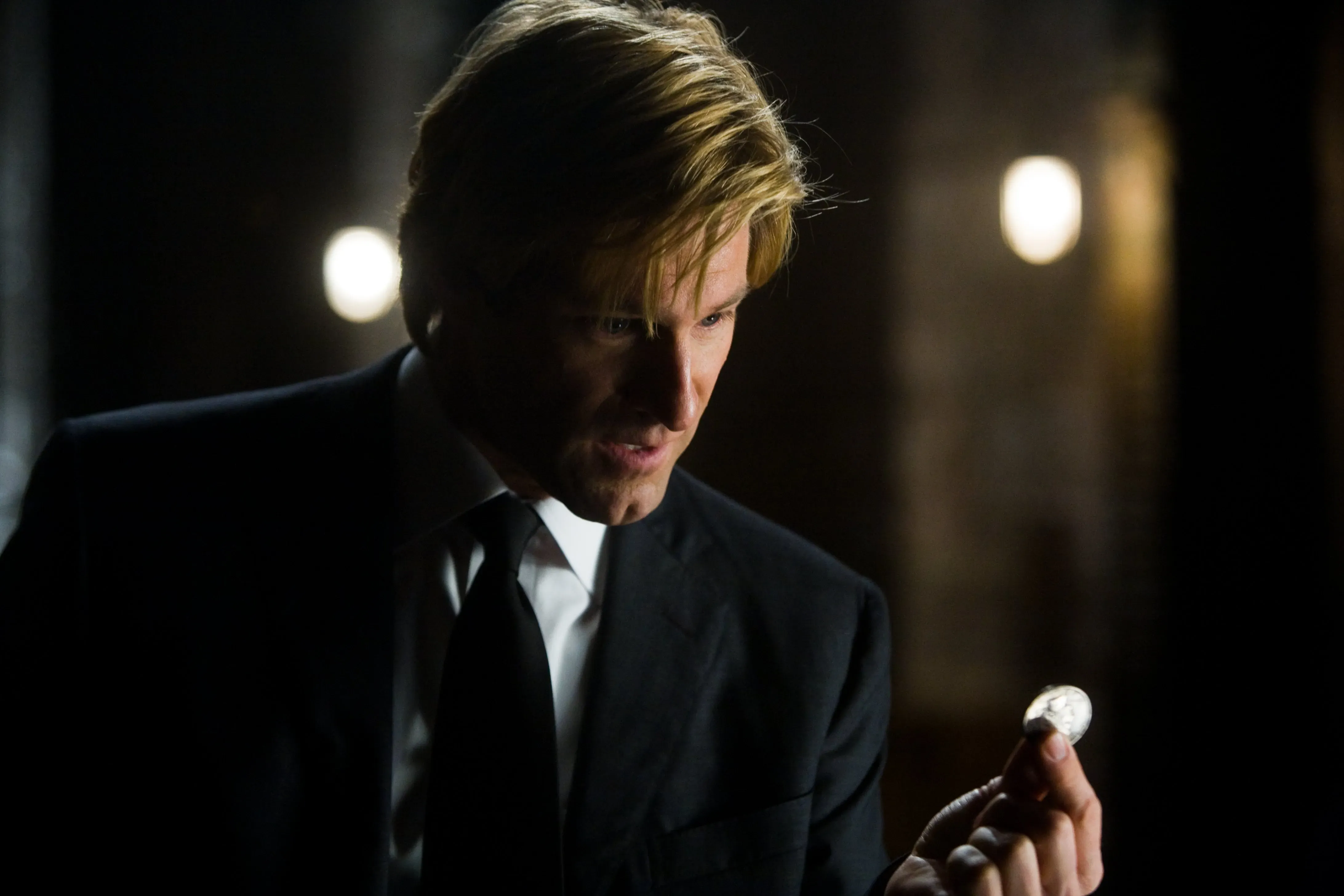 Harvey Dent in a black suit, holding out a coin, JPG.