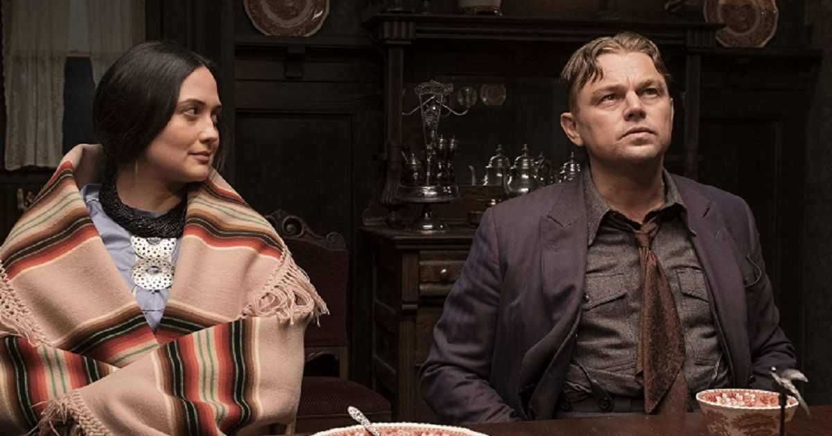 Lily Gladstone & Leonardo DiCaprio sit at a table in Killers of the Flower Moon