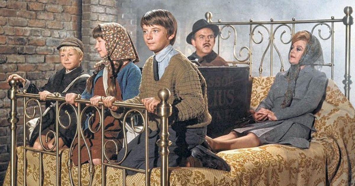 The main cast of bedknobs and broomsticks all gathered on a bed to transport them somewhere else