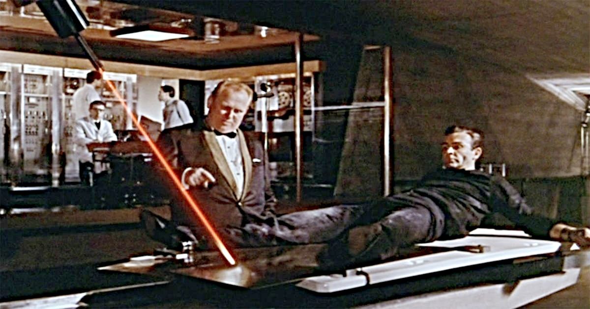 Goldfinger prende Bond a uma mesa em Goldfinger