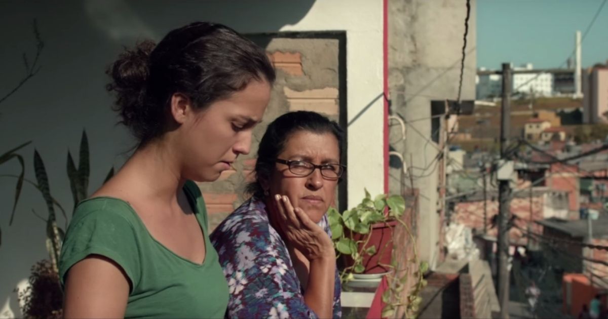 Duas mulheres estão na varanda de um antigo prédio de apartamentos no Brasil.