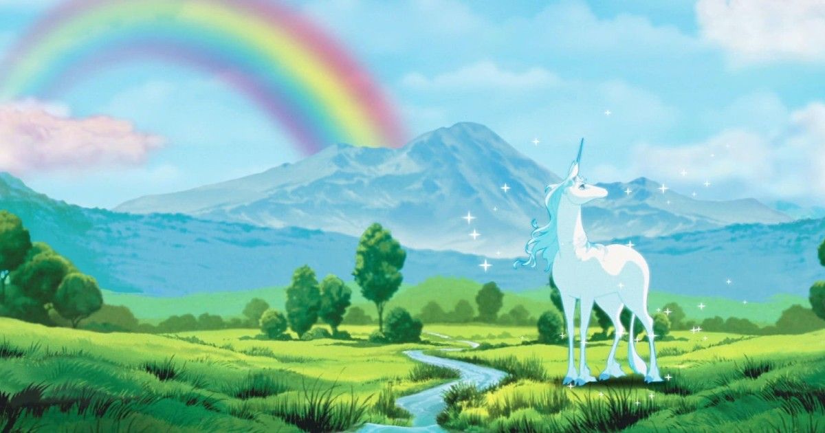 The last Unicorn stands looking over a valley with a rainbow behind her. 