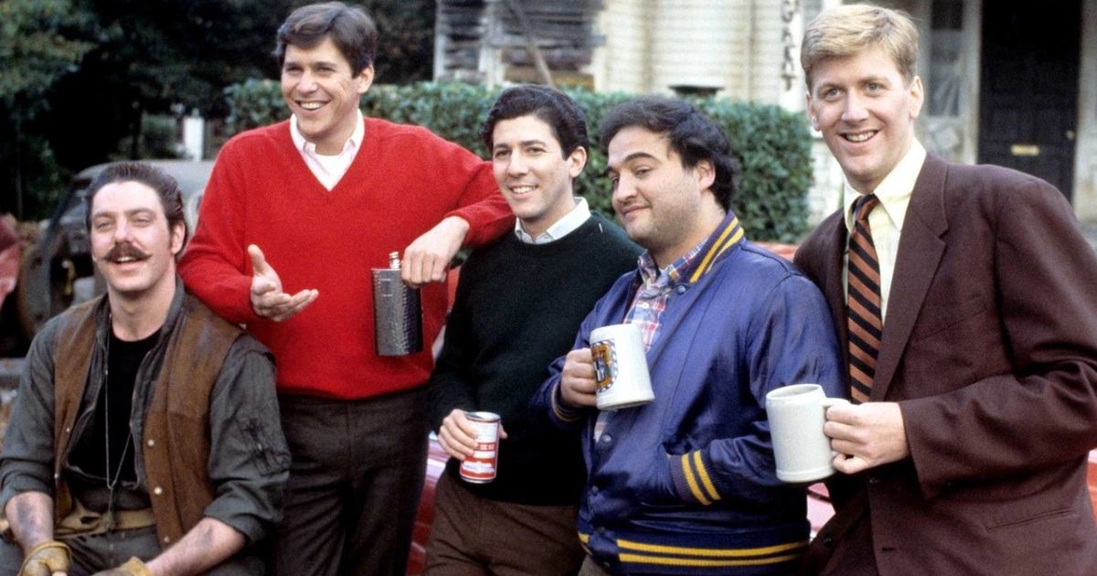 National Lampoon's Animal House cast with variuos drinks sitting outside their frat house.