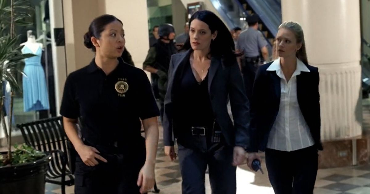 A police offer walking with Agent Emily Prentice (brunette) and Agent Jennifer Jarveau (blonde)