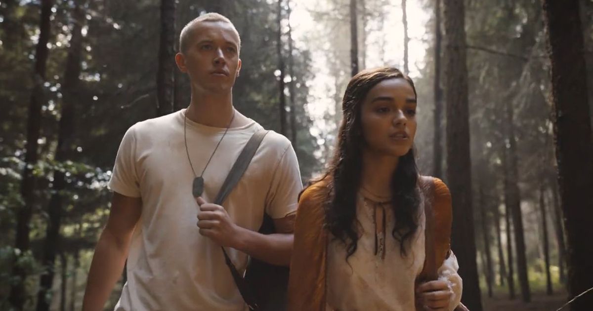 Rachel Zegler as Lucy Gray Baird and Tom Blyth as Coriolanus Snow walking through the forest in The Ballad of Songbirds and Snakes