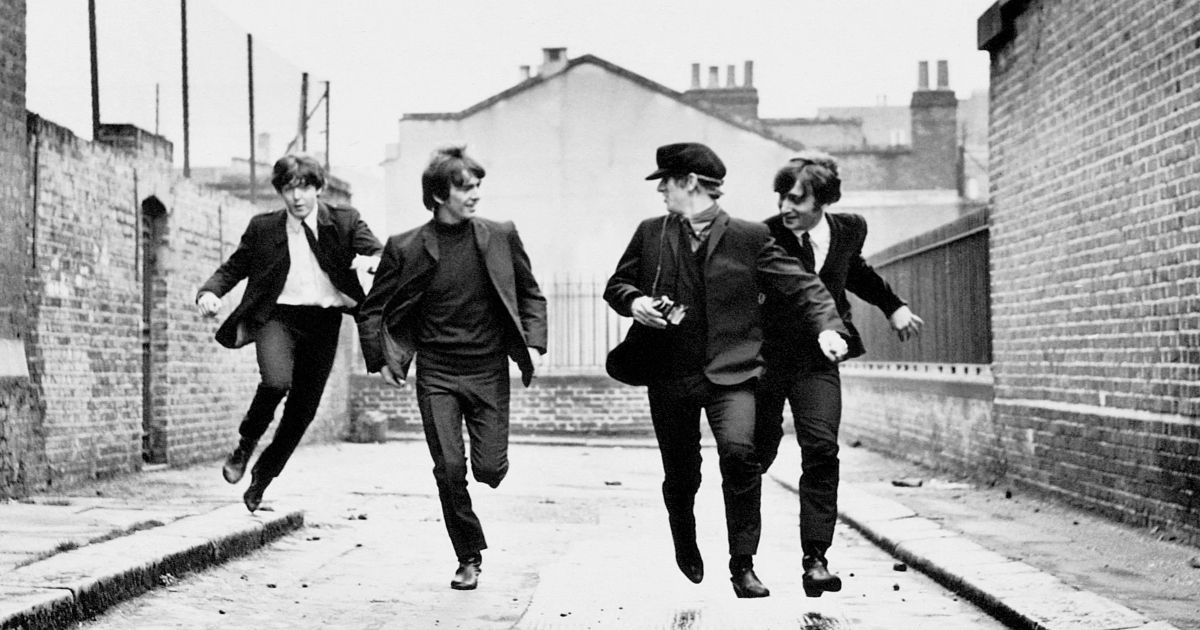The Beatles band, including Ringo Starr, Paul McCartney, John Lennon, and George Harrison running through an alleyway in A Hard Days Night