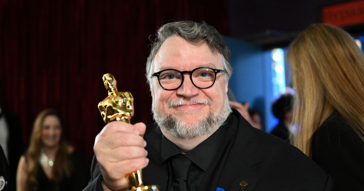 Guillermo del Toro holding an Oscar for his 2022 film Pinocchio.