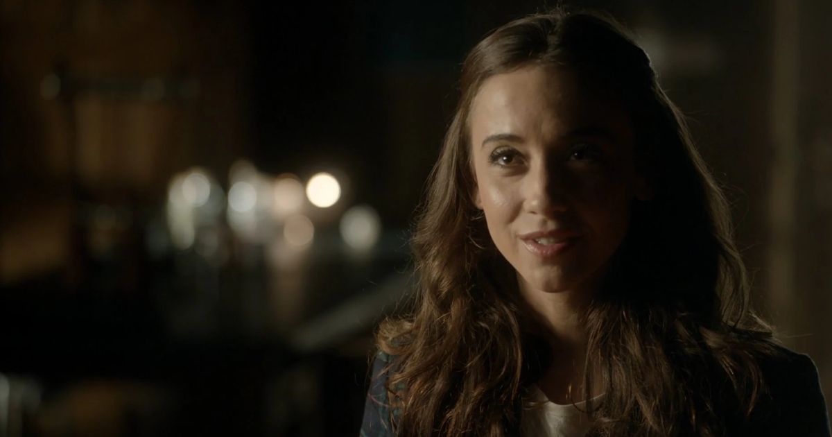 Julia, portrayed by Stella Maeve, standing outside in the night. She is smiling and staring into the distance (The Magicians)