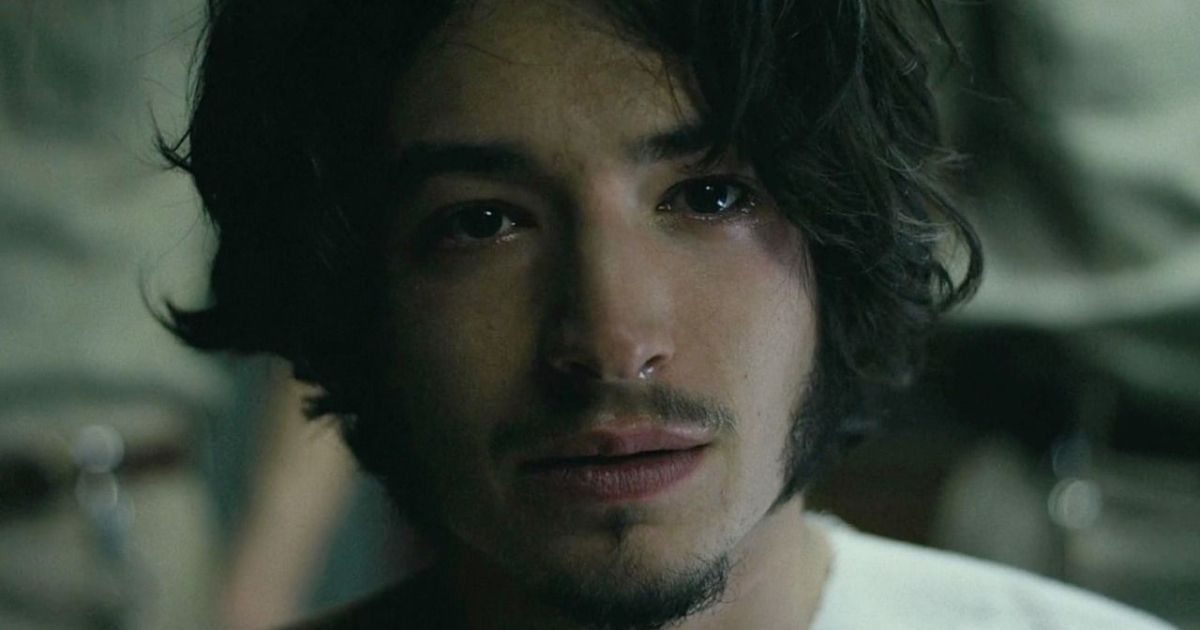 Ezra Miller vestindo uma camisa branca com cabelo comprido e cavanhaque em The Stanford Prison Experiment