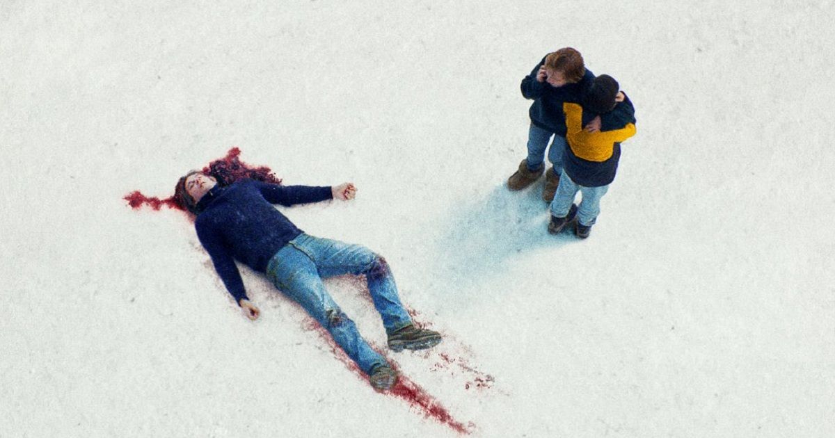 A mother and her child look down at a dead man, who is bleeding from his head.