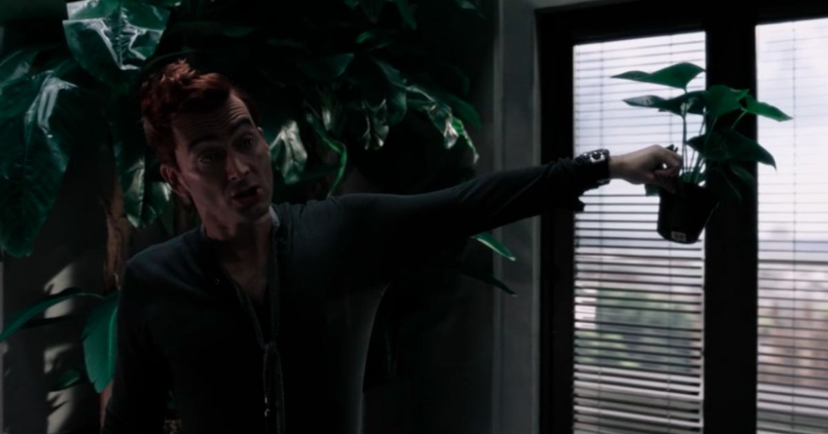 David Tennant como Crowley segurando uma planta