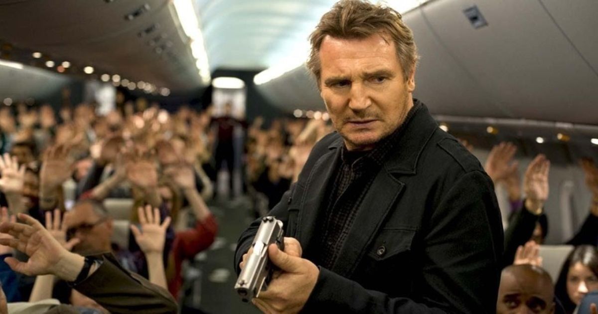 Liam Neeson holding a gun on the plane and passengers with their hands up in Non-Stop (2014)