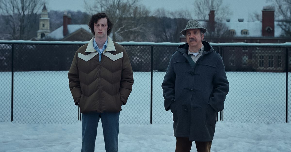 Paul Giamatti as Paul Hunham and Dominic Sessa as Angus Tully, standing outside with large coats on in the snow in The Holdovers