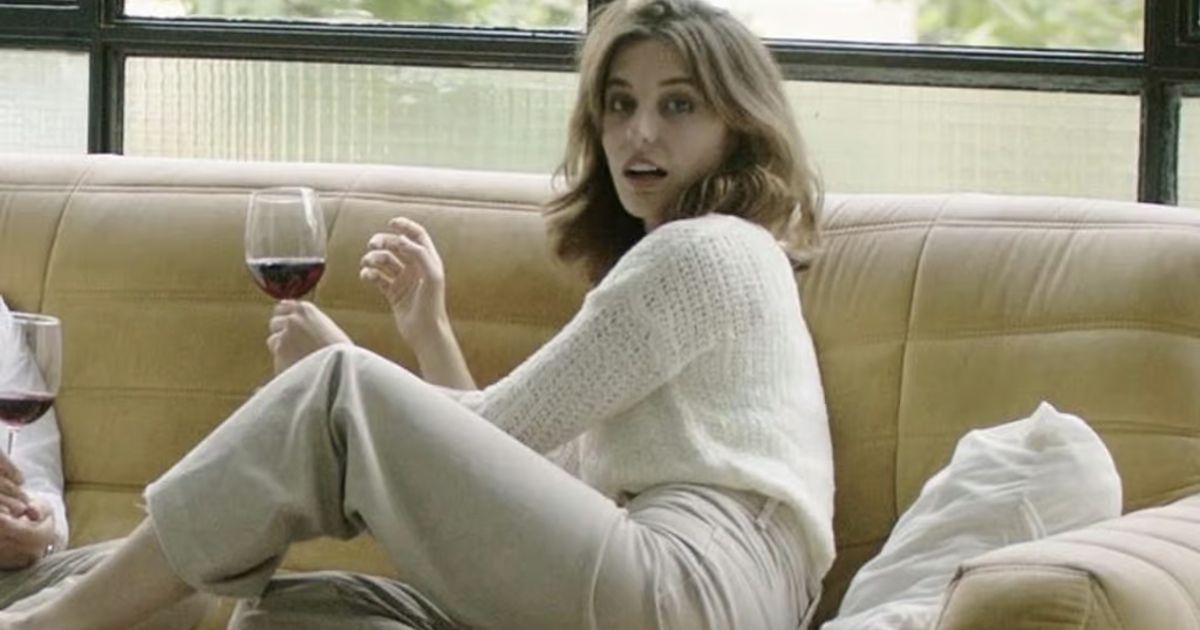 Ana holds a wine glass on a sofa in Who is Erin Carter?